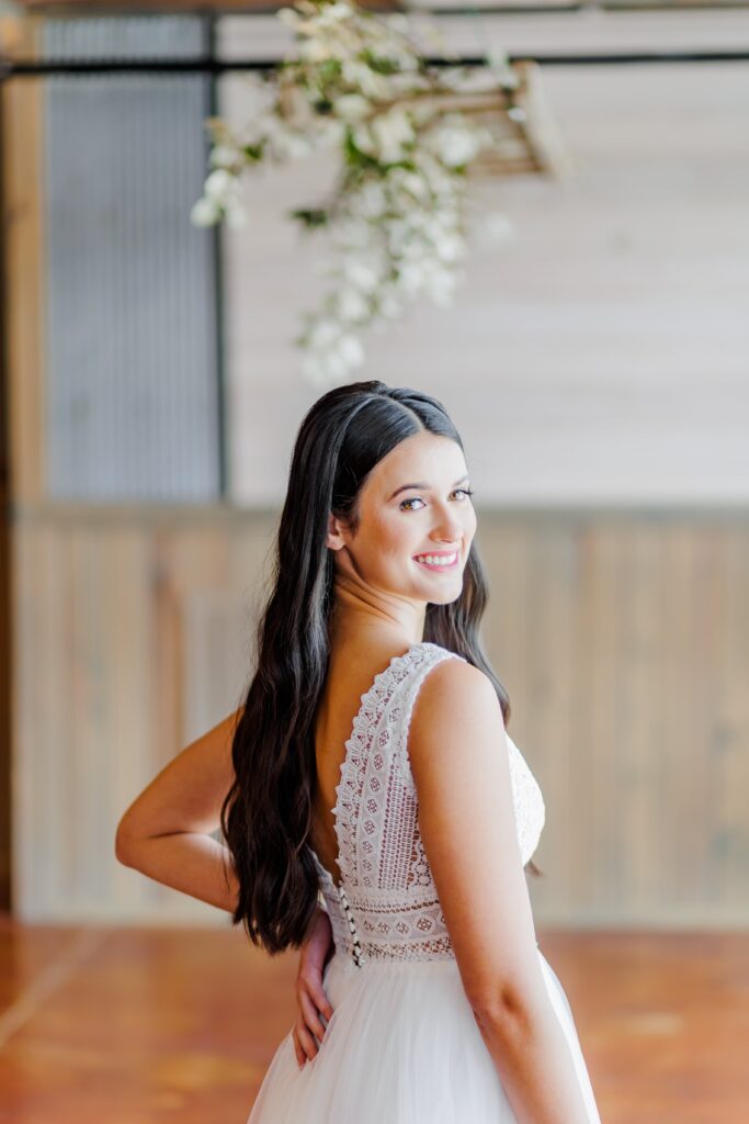 A gorgeous Arkansas Bride stands for a portrait showing off the back of her dress.