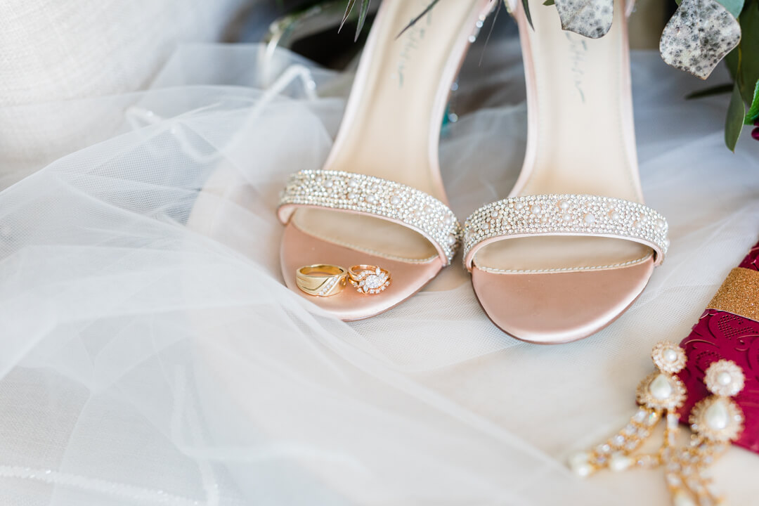 Wedding bands sit on a pair of shoes next to large gold and pearl earings cold springs wedding venue